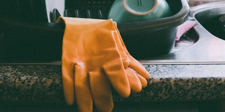 Cozy kitchen setup featuring a dish rack, dishes, and yellow gloves, ideal for a homey atmosphere.